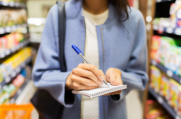 Image showing close up of woman writing to notepad in market