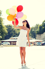 Image showing smiling young woman in sunglasses with balloons