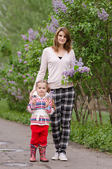 Image showing Young woman with a daughter in lilac bush