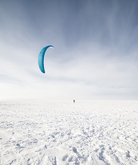 Image showing Kiteboarder with blue kite on the snow