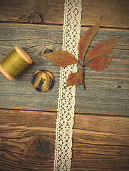 Image showing still life with lace ribbon, vintage buttons, spools of thread a