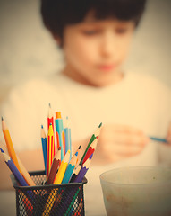 Image showing colored pencils for drawing in pencil holders and the child on b