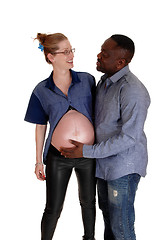 Image showing African man holding baby belly of white girl.