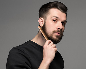 Image showing young man comb his beard and moustache 