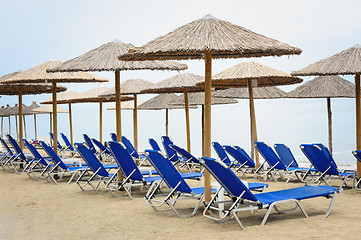 Image showing Reed umbrellas and deck chairs at the beach