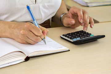 Image showing Woman typing on calculator