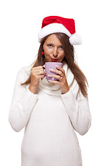 Image showing Cold young woman in a Santa hat sipping coffee tea