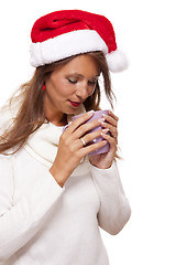 Image showing Cold young woman in a Santa hat sipping coffee tea