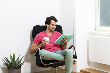 Image showing Man Sitting on Chair with Book and a Drink