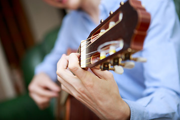 Image showing Young musician playing at acoustic guitar