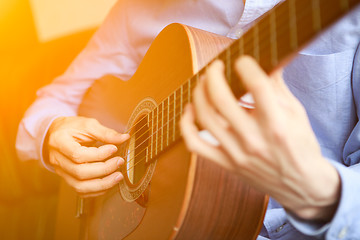 Image showing Young musician playing at acoustic guitar