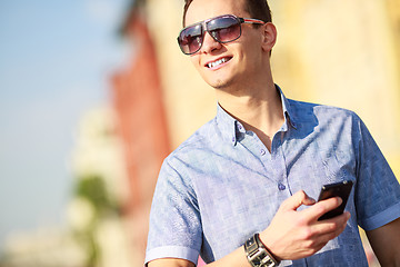 Image showing Outdoor portrait of man with mobile phone in the street.