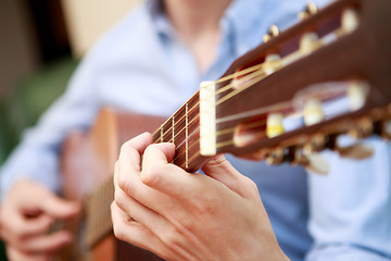 Image showing Young musician playing at acoustic guitar