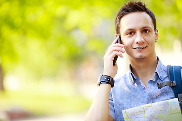 Image showing Man holding map outdoors and talking by phone