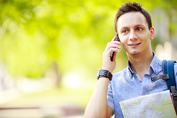 Image showing Man holding map outdoors and talking by phone