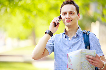 Image showing Man holding map outdoors and talking by phone