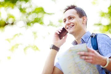 Image showing Man holding map outdoors and talking by phone