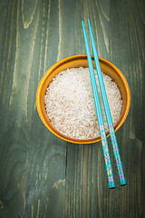 Image showing Uncooked rice grains in wood bowl