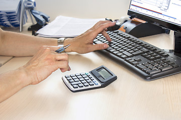 Image showing Businesswoman typing on calculator