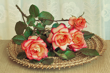 Image showing The roses on the table on a wicker platter.