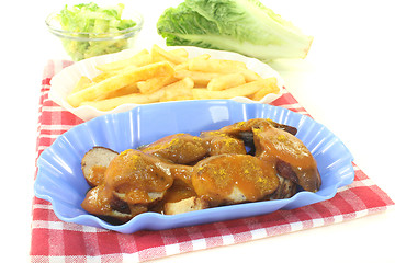 Image showing Currywurst with french fries on a napkin