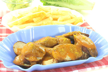 Image showing Currywurst with french fries on a checkered napkin