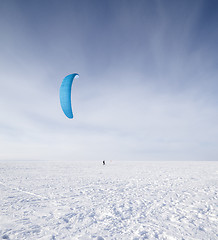 Image showing Kiteboarder with blue kite on the snow