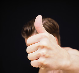 Image showing Caucasian male showing thumbs up covering face isolated on black