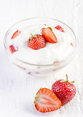 Image showing fresh organic yogurt with strawberries on wooden