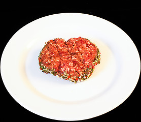 Image showing Seasoned raw red hamburger on white plate isolated on black