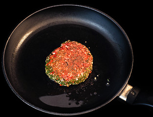 Image showing Raw red seasoned hamburger in fry pan isolated on black