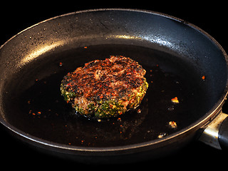 Image showing Frying seasoned hamburger in fry pan isolated on black