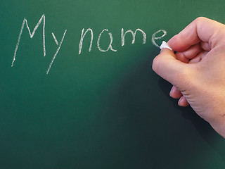 Image showing Person writing on green chalkboard; My name, with calk