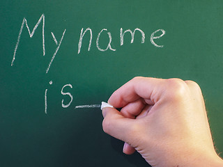 Image showing Teacher writing on green chalkboard: My name is