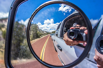Image showing  camera reflected in the rearview mirror of a car on a summer da