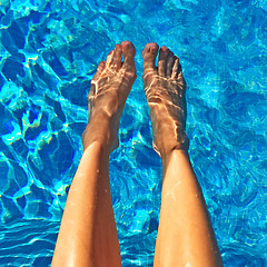 Image showing Female feet in blue water