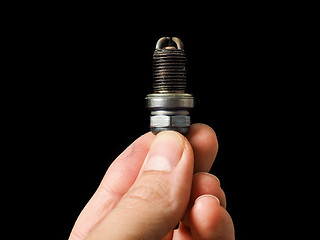 Image showing Hand of a male person holding a worn spark plug isolated on blac