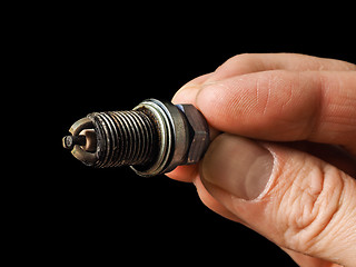 Image showing Closeup of a worn spark plug held by caucasian male fingers