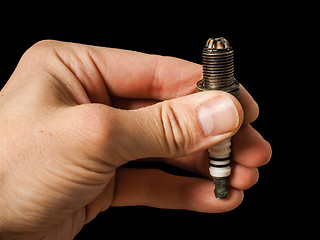 Image showing Closeup of a worn spark plug held by caucasian male fingers