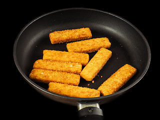 Image showing Crumbed fish fingers in fry pan, isolated on black