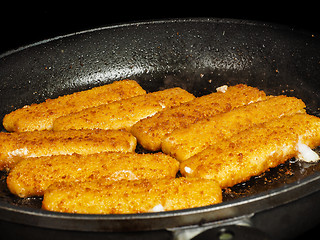 Image showing Closeup of crispy breaded fish fingers in hot fry pan