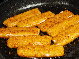 Image showing Closeup of crispy breaded fish fingers in hot fry pan
