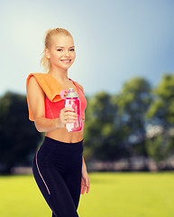 Image showing smiling sporty woman with water bottle and towel