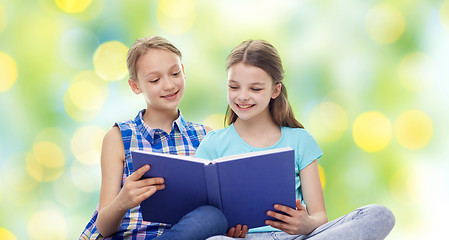 Image showing two happy girls reading book over green background