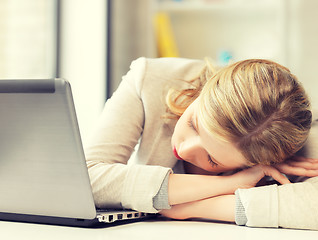 Image showing bored and tired woman sleeping on the table