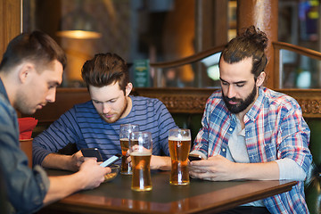 Image showing male friends with smartphones drinking beer at bar