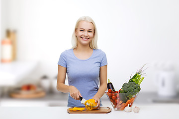 Image showing smiling young woman chopping vegetables on kitchen