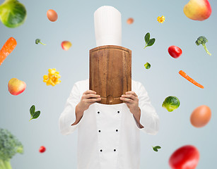 Image showing male chef cook covering face with cutting board