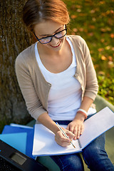 Image showing happy student girl writing to notebook at campus