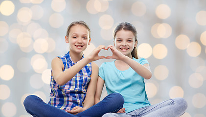Image showing happy little girls showing heart shape hand sign